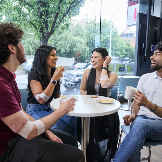 a group of people sitting around a table with snacks and drinks laughing and chatting