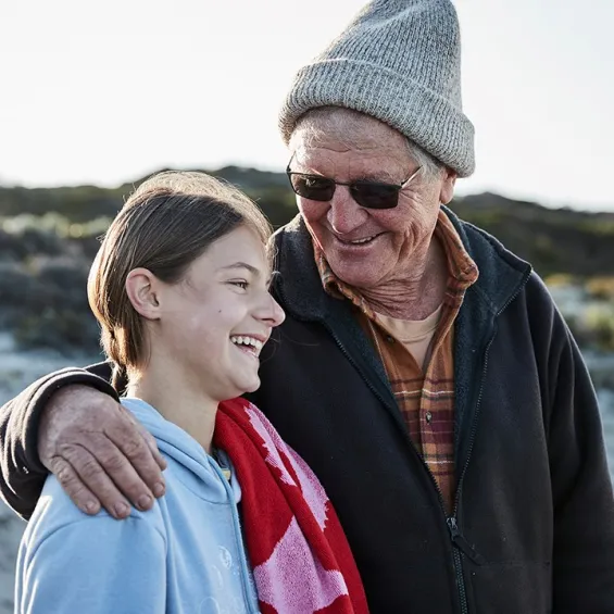 a child and adult standing on a beach