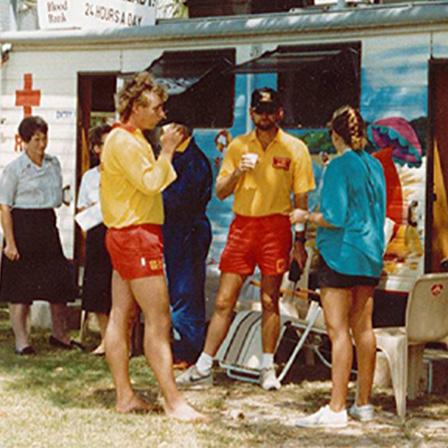1990s colour photo of two groups of three people outside donor mobile. One group is administration staff. The other are donors talking while holding refreshments.