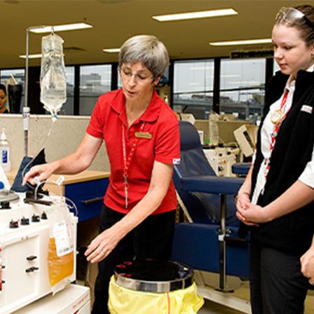 staff member showing two newer staff members the plasma donation machine in a donation centre