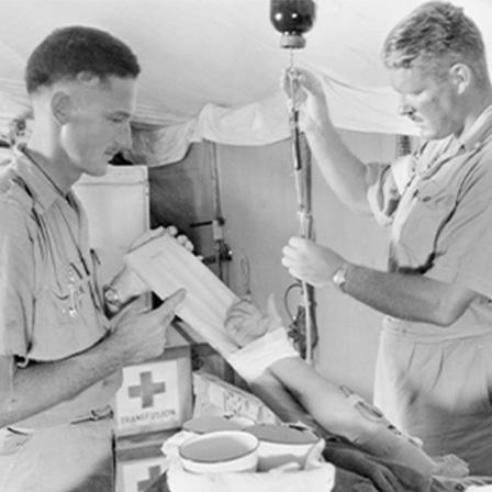 two male doctors in war-time medical tent working on a patient