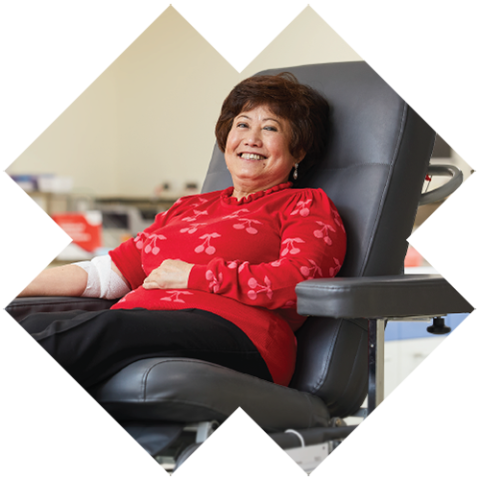 a woman in a donor chair smiling with a bandage around her elbow