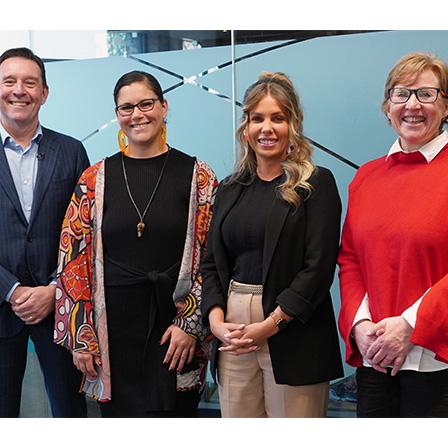 four people in a meeting room smiling at the camera