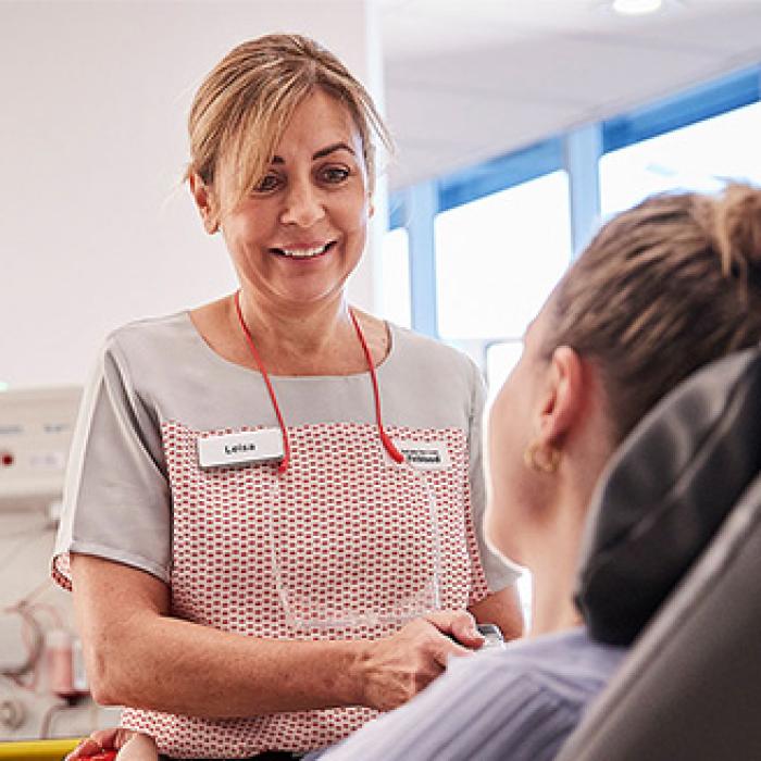 a nurse smilling at a person seated making a donation