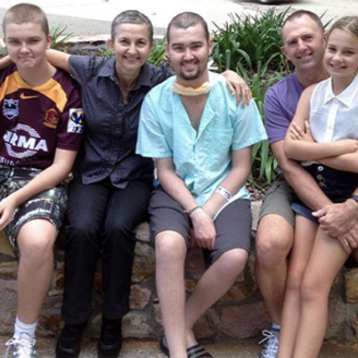a family of five seated outside smiling to the camera