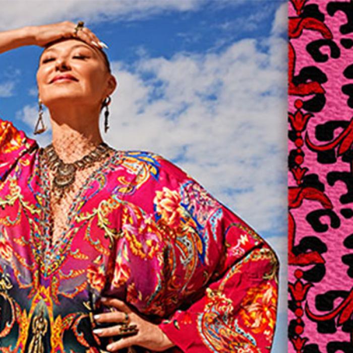 photo of camilla franks with a sky backdrop, she is wearing a pink patterned dress and has the bandage she designed around her right elbow